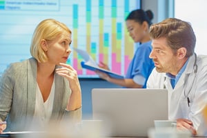 male doctor and female businesswoman chat over the ways Higher Elevation can help them maintain compliance 